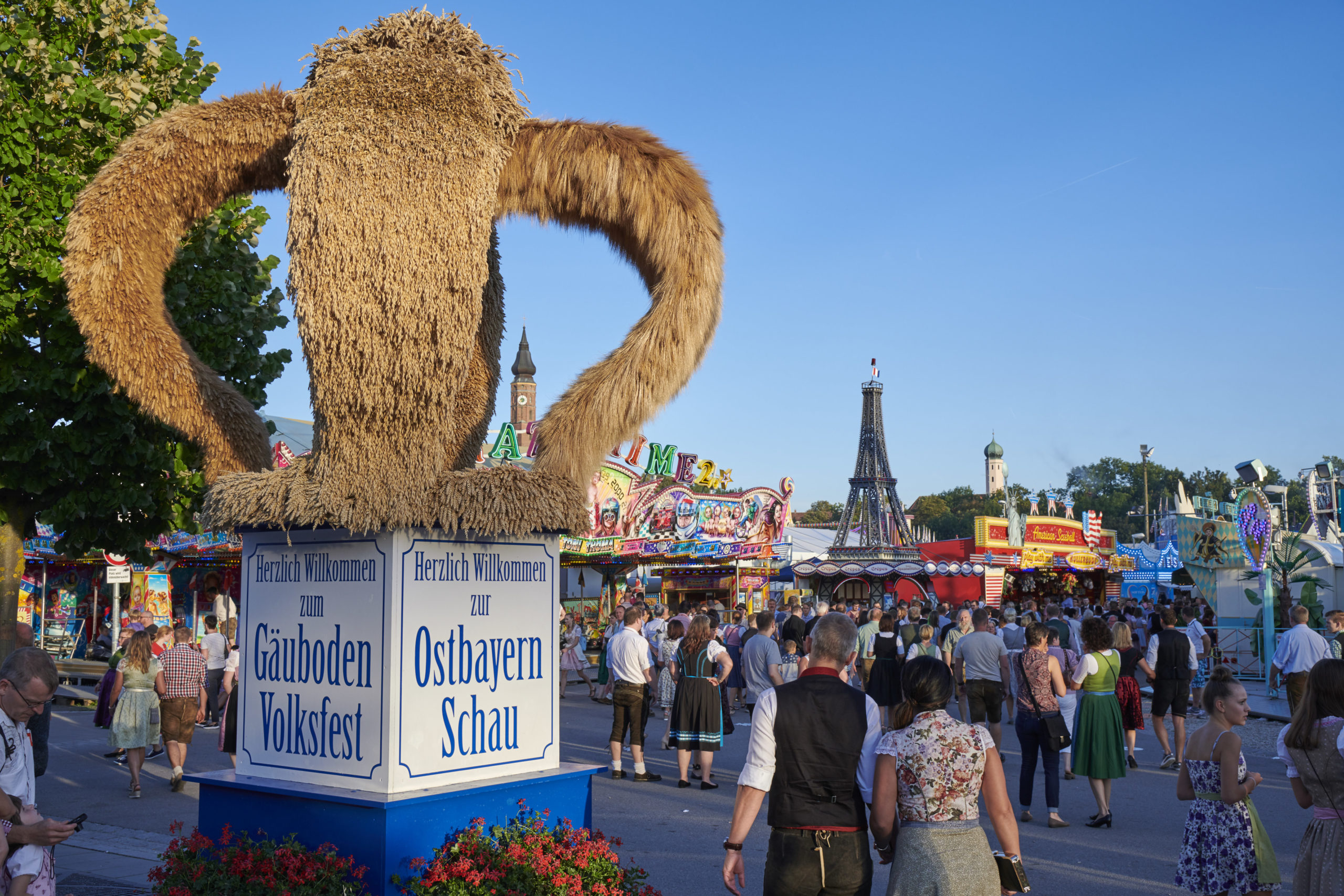 Erntekrone am Gäubodenvolksfest Straubing mit Fahrgeschäften im Hintergrund